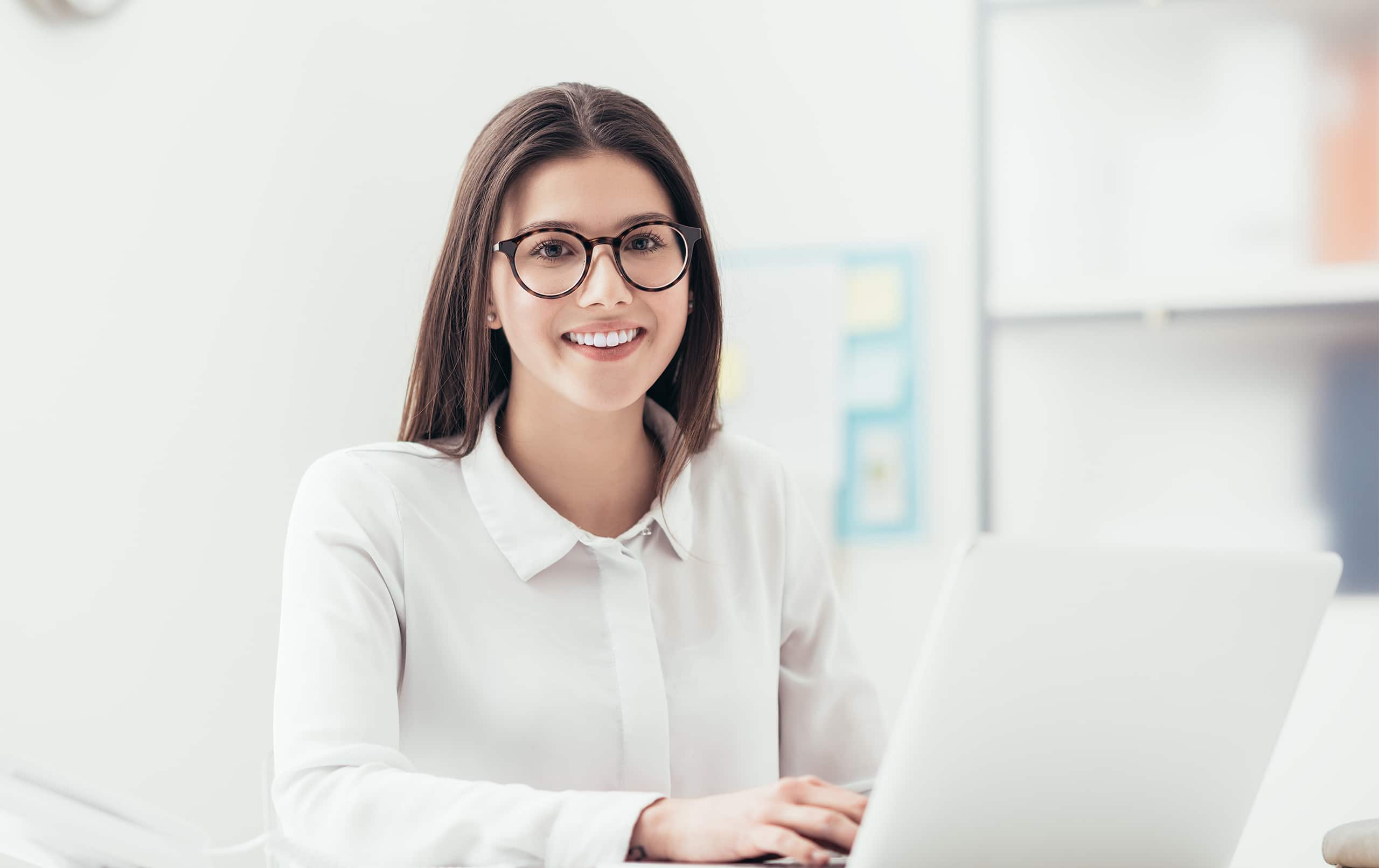 Frau sitzt vor Laptop und lacht in die Kamera. Bewerben Sie sich als Mitarbeiter / Assistenz (m/w/d) Marketing & Onlinevertrieb