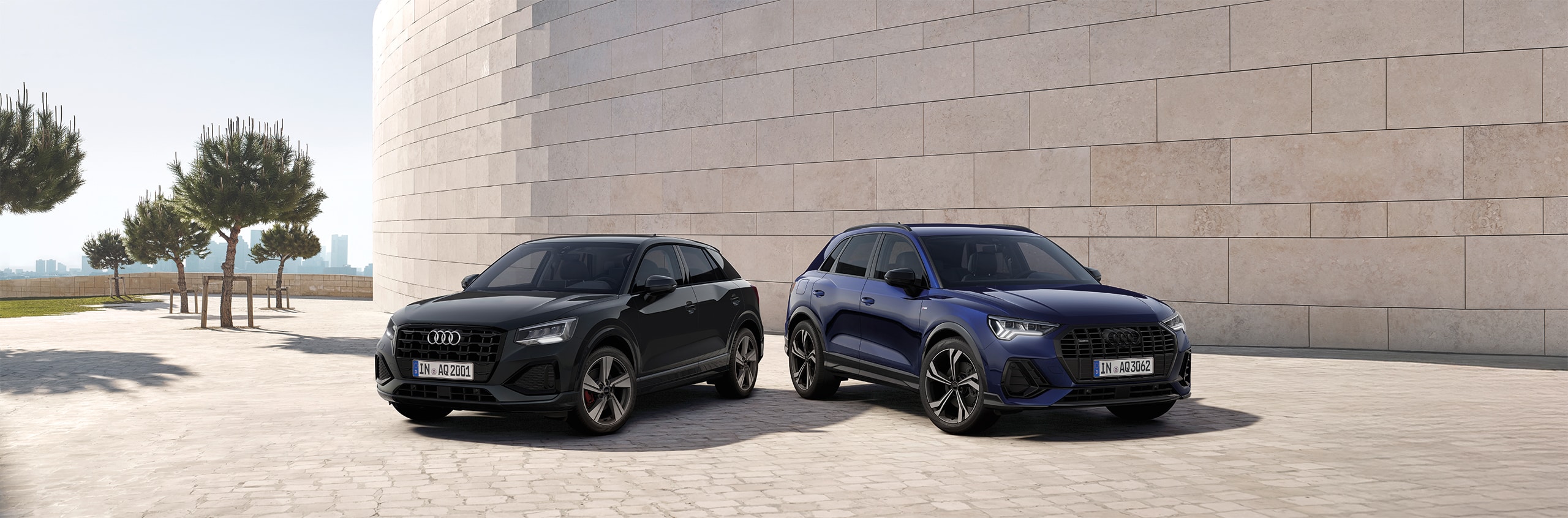 Schwarzer und dunkelblauer Audi stehen nebeneinander vor einer Steinwand.