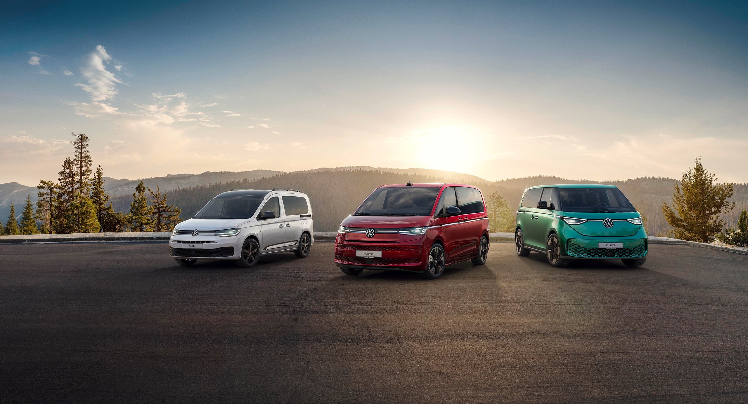 Drei Volkswagen stehen vor einem Wald mit Sonnenuntergang im Hintergrund.